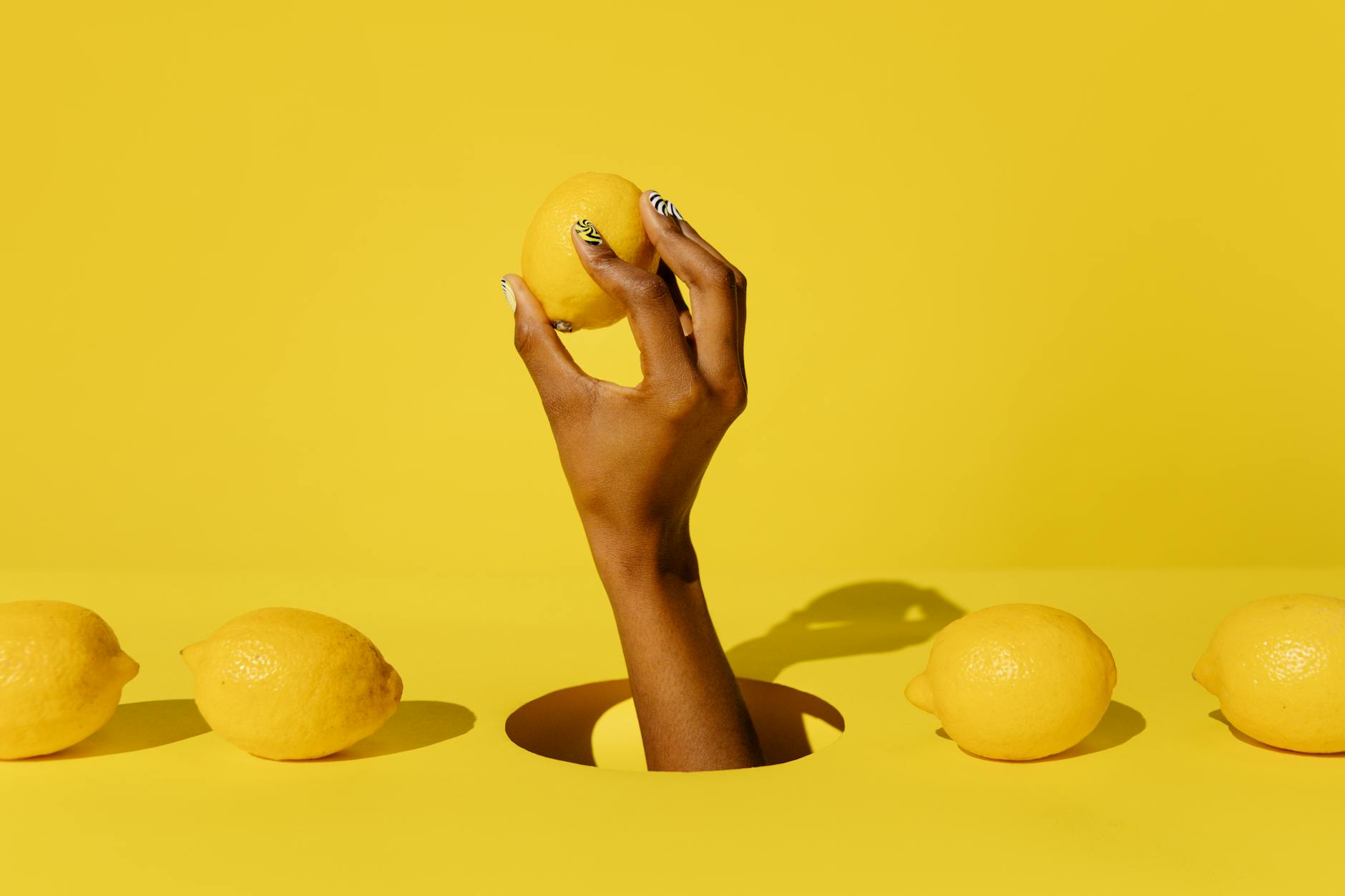A hand holding a fresh lemon against a vivid yellow background, symbolizing the shifting nature of pleasure throughout the cycle